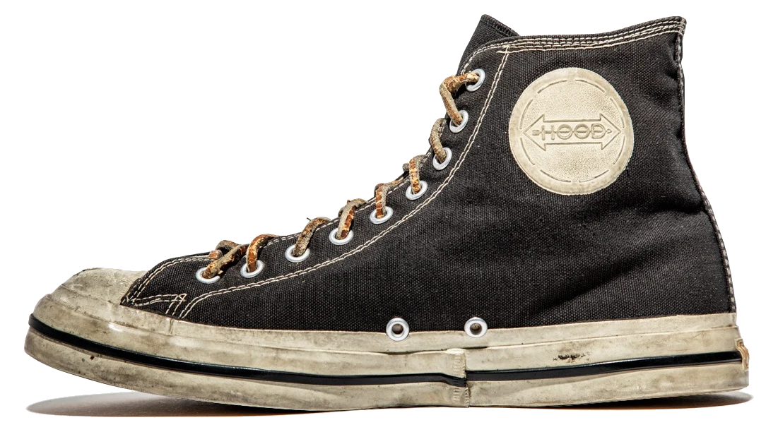 A surviving 1955 Hood Conference in profile: black cotton duck upper, cream rubber foxing carrying a single black stripe, a plain moulded toe cap and a white rubber disc at the ankle.